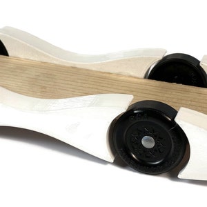 May include: A white wooden soapbox derby car with black wheels. The car has a curved design and is made of wood.