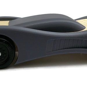 Peut inclure: Une voiture de course en bois et grise avec des roues noires. La voiture a un design élégant et aérodynamique.