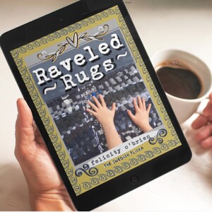May include: A black tablet displays the cover of a book titled "Raveled Rugs" with a blue, gray, and white rug design. The author's name, Felicity O'Brien, is also visible. A cup of coffee is in the background.
