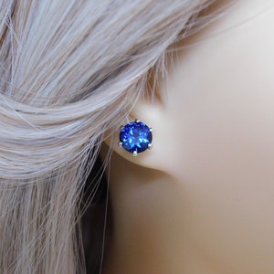 May include: A pair of silver stud earrings with a large, round, dark blue gemstone.