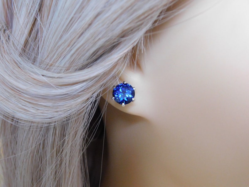 May include: A pair of silver stud earrings with a large, round, dark blue gemstone.