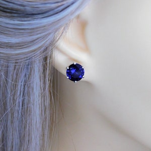 May include: A pair of silver stud earrings with a large, round, dark blue gemstone.