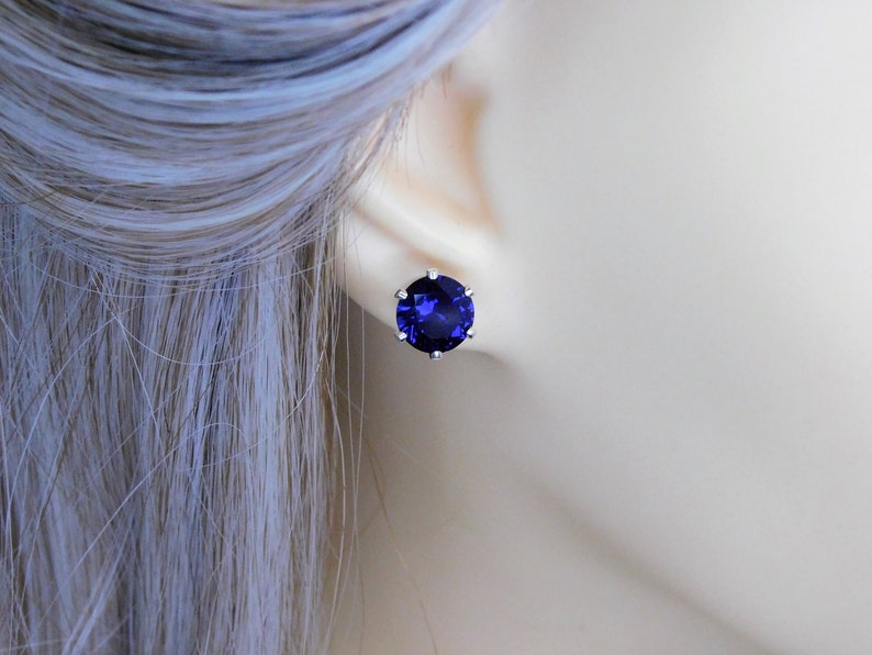 May include: A pair of silver stud earrings with a large, round, dark blue gemstone.