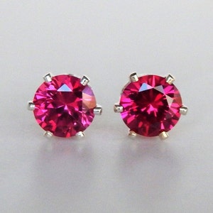 May include: A pair of silver stud earrings with bright pink round gemstones.