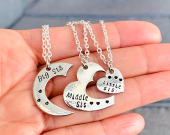 May include: Three silver necklaces with heart-shaped pendants. The pendants say "Big Sis", "Middle Sis", and "Little Sis".