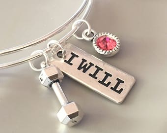 May include: Silver bangle bracelet with three charms: a dumbbell, a pink rhinestone, and a silver tag that says "I WILL".