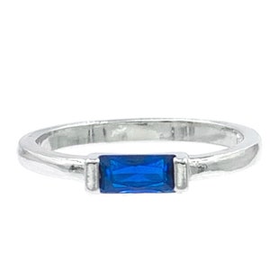 May include: A silver ring with a blue rectangular gemstone.
