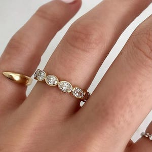 May include: A gold band ring with a row of oval-shaped diamonds set in the band.