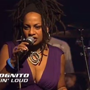 May include: A woman with long dreadlocks sings into a microphone while wearing a purple dress and a silver necklace. The text "INCOGNITO TALKIN' LOUD" is visible in the bottom left corner of the image.