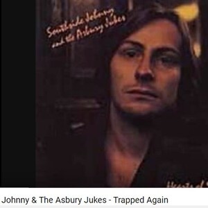 May include: A vintage record album cover featuring a man with long brown hair. The album title is "Southside Johnny and the Asbury Jukes - Trapped Again".