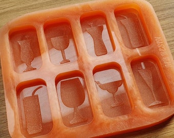 Op de afbeelding: Oranje siliconen mal met negen verschillende drankvormen, waaronder een margarita glas, een wijnglas, een champagnefluit en een cocktailglas. De mal is gelabeld "MISTER B's".
