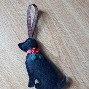May include: Black felt dog ornament with a red and green ribbon and holly berry accents.