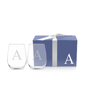May include: Two clear stemless wine glasses with the letter "A" etched on them, presented with a blue gift box tied with a white ribbon. The box also features the letter "A".