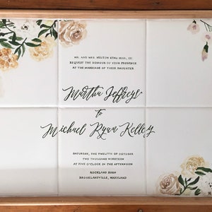 Puede incluir: Una bandeja de cerámica blanca con marco de madera, decorada con diseños florales y el texto "Mr. and Mrs. Milton King Hill, III request the honour of your presence at the marriage of their daughter Martha Jeffreys to Michael Ryan Kelley Saturday, the twelfth of October two thousand nineteen at five o'clock in the afternoon Rockland Barn Brooklandville, Maryland".