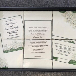 Puede incluir: Una bandeja negra contiene seis baldosas blancas con anuncios de boda y dise&ntilde;os florales. Las baldosas presentan texto como "Save the Date" y "Mabuhay and Welcome to Manila!" en negro. Hay detalles florales verdes y blancos.
