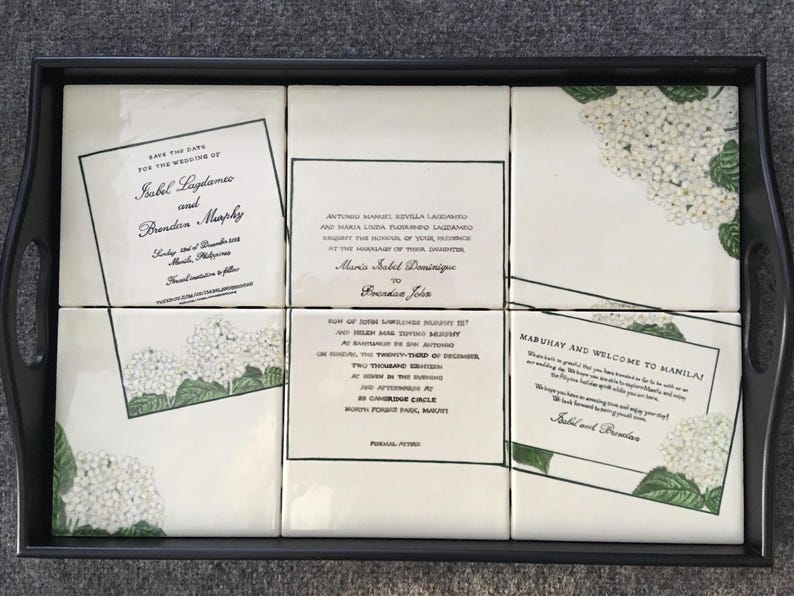 Puede incluir: Una bandeja negra contiene seis baldosas blancas con anuncios de boda y dise&ntilde;os florales. Las baldosas presentan texto como "Save the Date" y "Mabuhay and Welcome to Manila!" en negro. Hay detalles florales verdes y blancos.