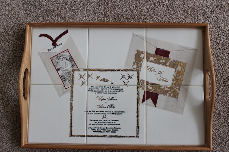 Puede incluir: Bandeja decorativa con marco y asas de madera. La superficie de baldosas blancas presenta dise&ntilde;os tem&aacute;ticos de boda, incluyendo invitaciones y una tarjeta "Save the Date". El dise&ntilde;o incluye detalles en color burdeos.