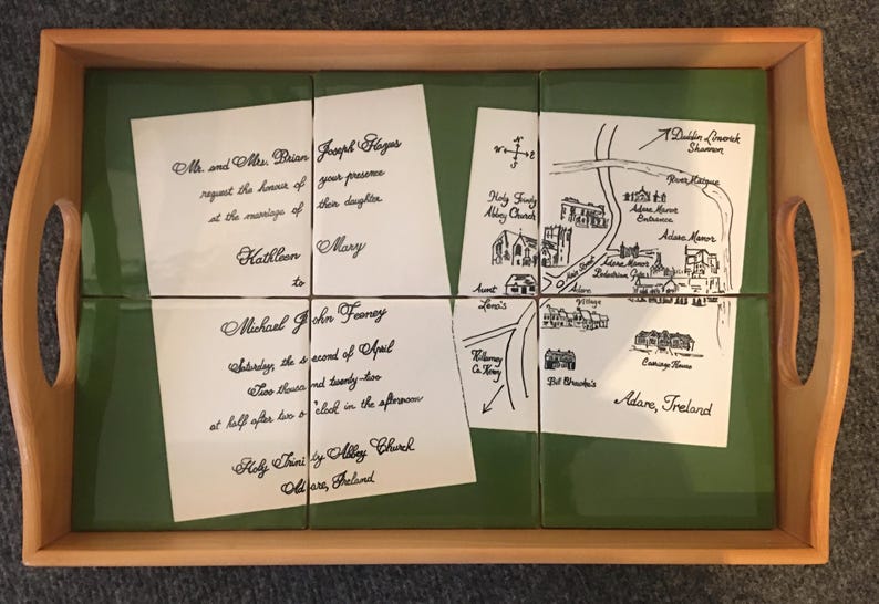 Puede incluir: Una bandeja de madera con una inserci&oacute;n de azulejos verdes, que contiene cuatro azulejos blancos con texto manuscrito negro. Los azulejos muestran detalles de boda, incluyendo un mapa y nombres.
