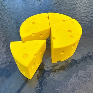 Puede incluir: Un conjunto de seis cuñas de queso de espuma amarilla, con forma de rueda de queso. Cada cuña tiene una superficie texturizada que se asemeja al queso suizo.