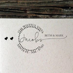 Puede incluir: Un sobre marrón con un sello de dirección de devolución en blanco y negro. El sello dice "2346 Wistful Vista Jacobs Beth & Mark Santa Fe - NM - 87501".