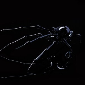 May include: A black glass spider sculpture with a shiny finish. The spider has eight legs and a round body with a reflective surface.