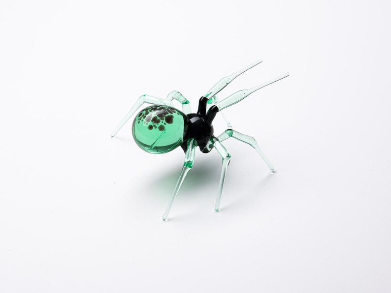 May include: A green glass spider with black accents and a speckled abdomen.