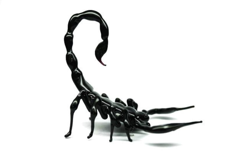 May include: A black glass scorpion sculpture with a curled tail and detailed legs. The scorpion is posed in a defensive stance with its stinger raised.