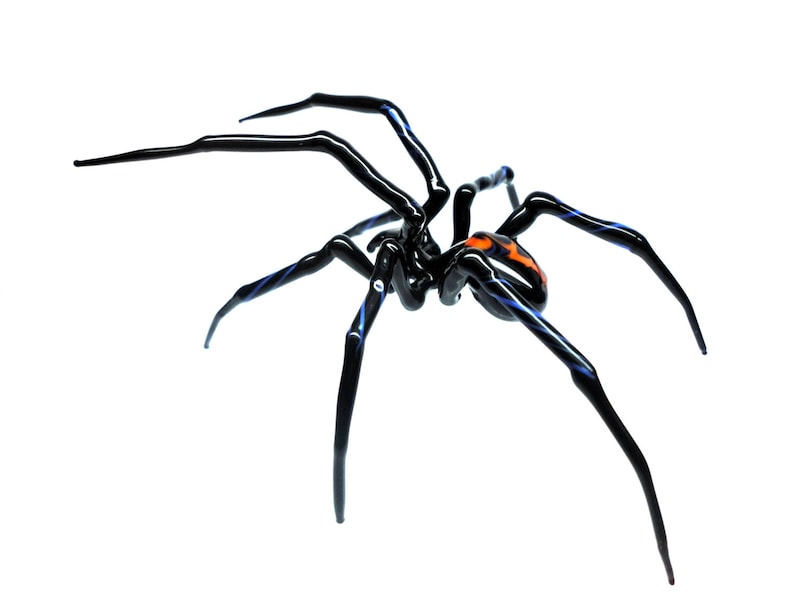 Puede incluir: Una escultura de ara&ntilde;a de vidrio negro con detalles en azul y naranja. La ara&ntilde;a tiene ocho patas y un cuerpo detallado.