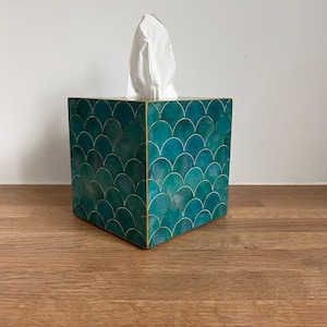 May include: Teal tissue box cover with a scale pattern. The cover is made of wood and has a gold trim.