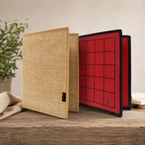 May include: A set of three open game boards. The two outer boards are covered in a tan burlap material with a beige trim. The inner board is red with a black grid pattern. The boards are displayed on a wooden surface.