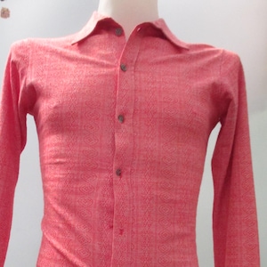 May include: A coral-colored long-sleeve shirt with a subtle geometric pattern. The shirt features a classic collar, button-down front, and buttoned cuffs. The shirt is displayed on a mannequin.