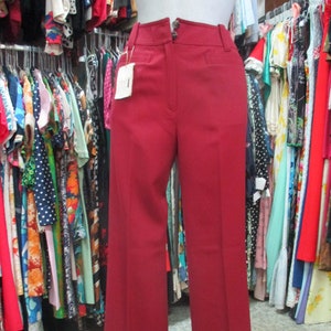 Könnte beinhalten: Eine weitbeinige, burgunderfarbene Hose mit hoher Taille und Knopfverschluss. Die Hose ist aus einem glatten, gewebten Stoff gefertigt.