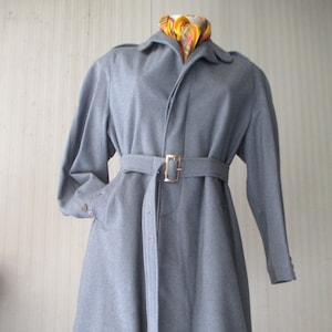 May include: A gray wool coat with a belt and a long, flowing silhouette. The coat has a classic design and is perfect for colder weather.