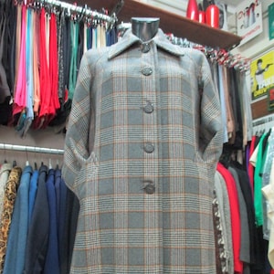 May include: A long gray and orange plaid coat with a button closure. The coat has a collar and pockets.