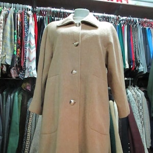 May include: A long, beige wool coat with a button closure and two large pockets. The coat is hanging on a rack in a clothing store.