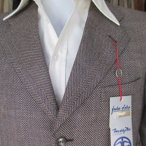 May include: A brown and white herringbone blazer with a red string and a tag that reads "Judo Doro" and "Zmargotto Confezioni".