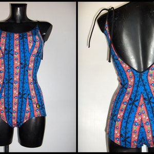 May include: A blue and pink swimsuit with a floral pattern and black straps. The swimsuit has a low back and a fitted bodice.