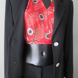May include: A black blazer with a red halter top featuring a white floral pattern and geometric design. The outfit includes black pants, creating a classic and stylish ensemble.