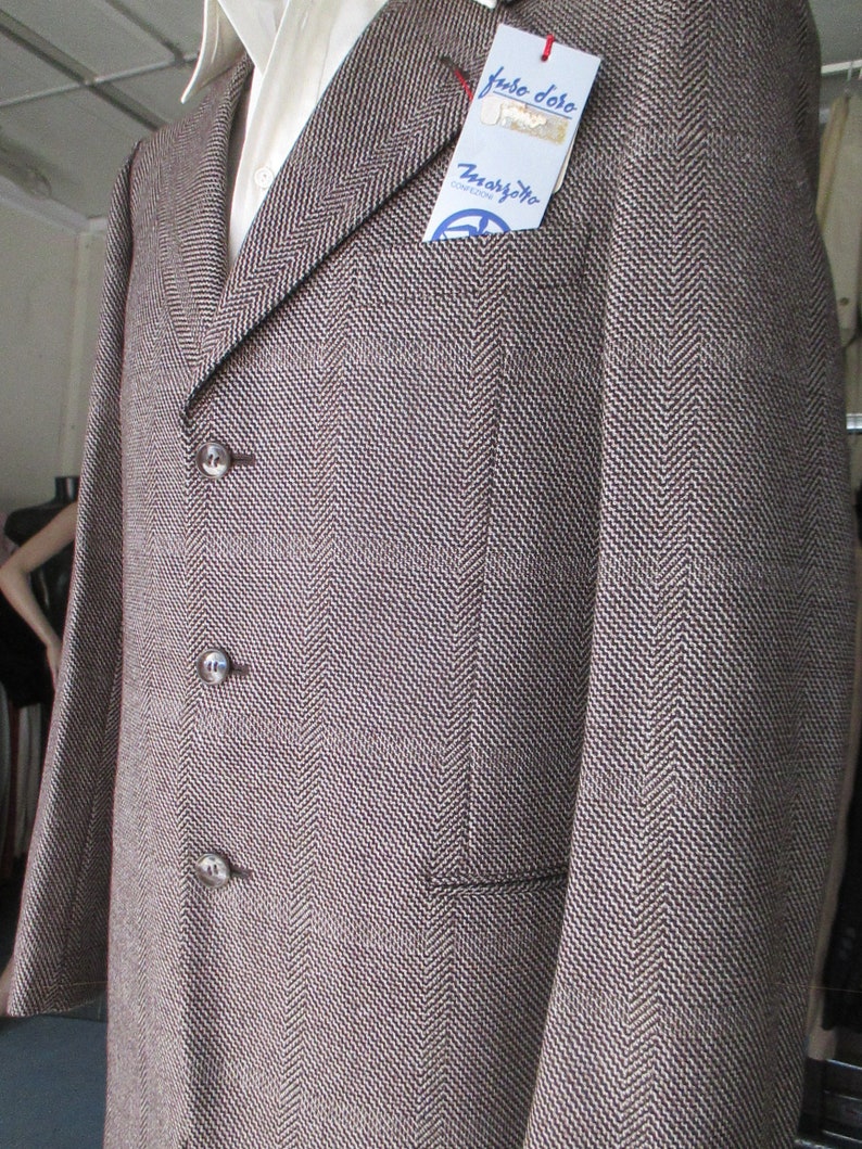 May include: A brown and white herringbone blazer with three buttons and a pocket on the left side. The blazer has a label that says "T. Marzotto" and "Fuso Doro".