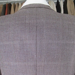 May include: A brown and white herringbone blazer. The blazer is made of a textured fabric and has a classic style.
