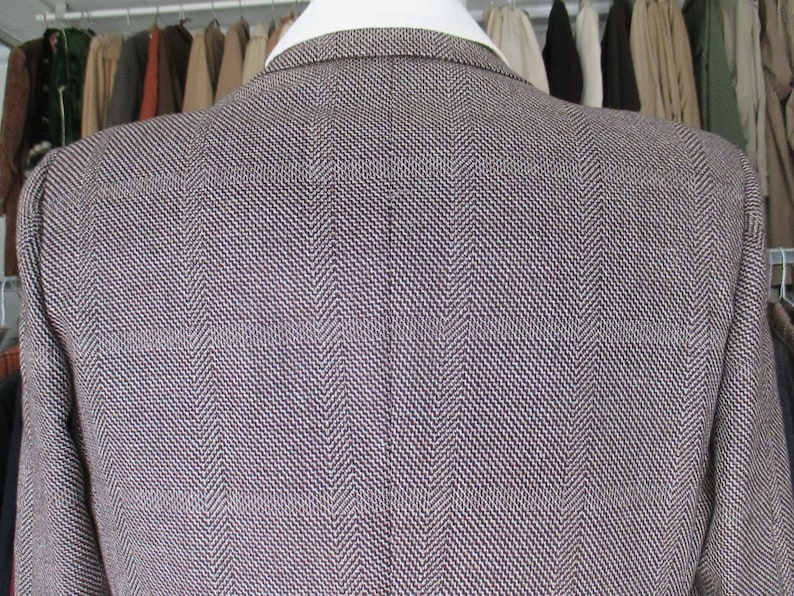 May include: A brown and white herringbone blazer. The blazer is made of a textured fabric and has a classic style.