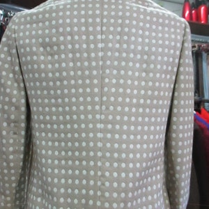 May include: A beige blazer with a white polka dot pattern. The blazer is cropped and has a collar.
