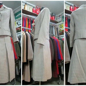 May include: A beige skirt suit with a white polka dot pattern. The jacket has a button closure and the skirt is pleated.