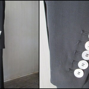 May include: A dark navy blue suit, featuring a tailored blazer with white buttons on the sleeve and matching trousers. The suit is displayed against a neutral background, showcasing its classic design and professional style.