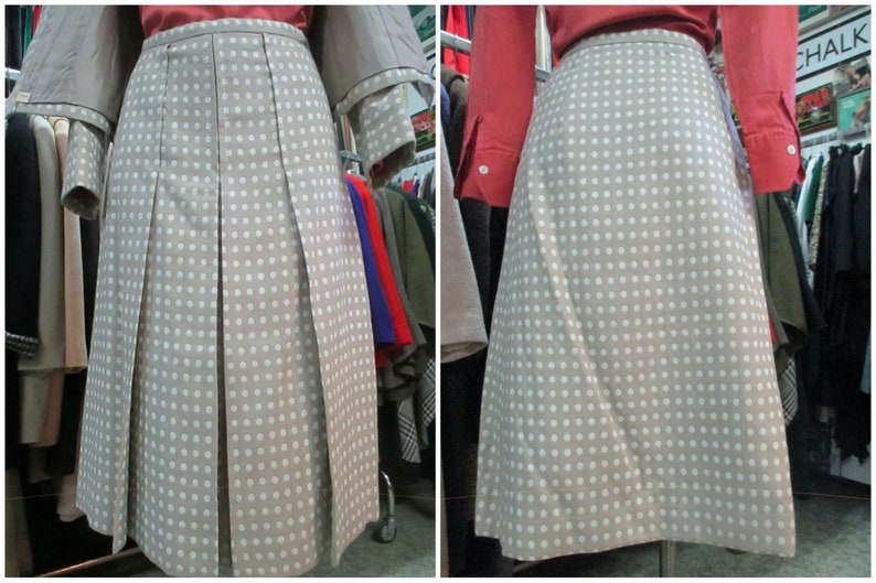 May include: A beige skirt with white polka dots and pleats. The skirt is knee-length and has a simple design.
