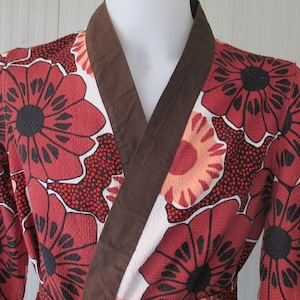 May include: A white robe with a brown collar and large red, orange, and black floral print.