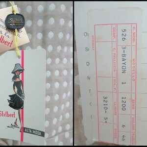 May include: A beige and white polka dot fabric with a white tag attached. The tag features a black and white illustration of a woman wearing a black dress and a hat. The tag also has the text "Stylbert Alta Moda".