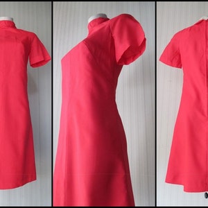 May include: A red vintage dress with a high neck and short sleeves. The dress has a simple, A-line silhouette.