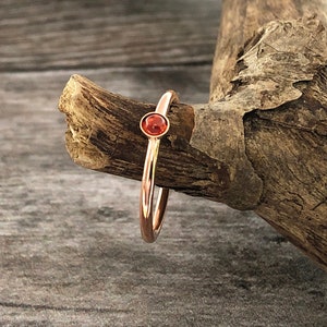 May include: A delicate gold ring with a small, round, orange gemstone.