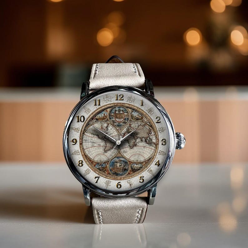 May include: A silver wristwatch with a cream-colored leather band. The watch face features a vintage world map design with Roman numerals. The watch has a classic, elegant style.